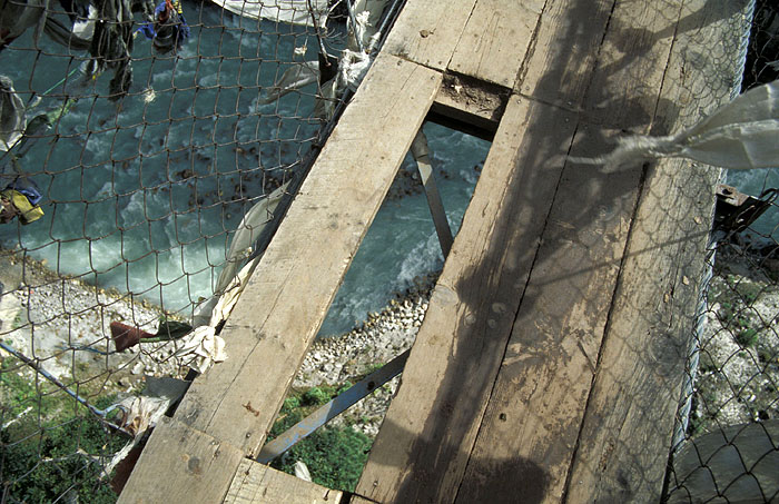 Missing planks in the Larja Bridge (2830m) - The bridge hovers above a canyon at the meeting of the Dudh Koshi River and the Bhote Koshi River and marks the beginning of the arduous climbing up 610m of altitude to Namche Bazaar (3440m)
<br>
Photo: Robert Downie - 2004 (EOS 300)